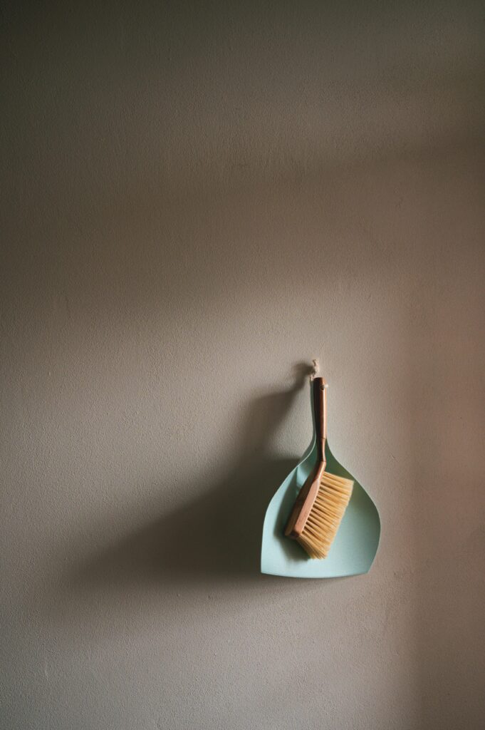 pexels photo 3972703 3972703 A simple dustpan and brush set hanging against a clean grey wall, perfect for cleaning concepts.